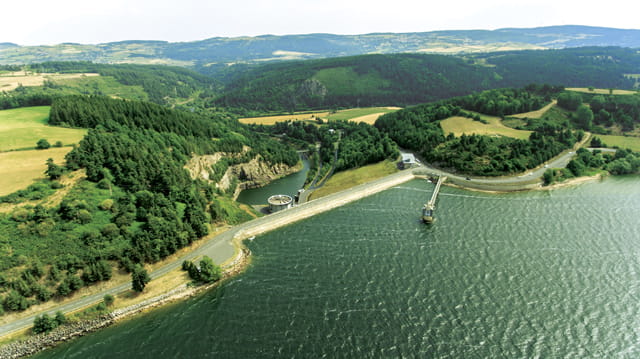 Photo composée au premier plan de la retenue d'eau, au plan intermédiaire du barrage de Naussac en Lozère